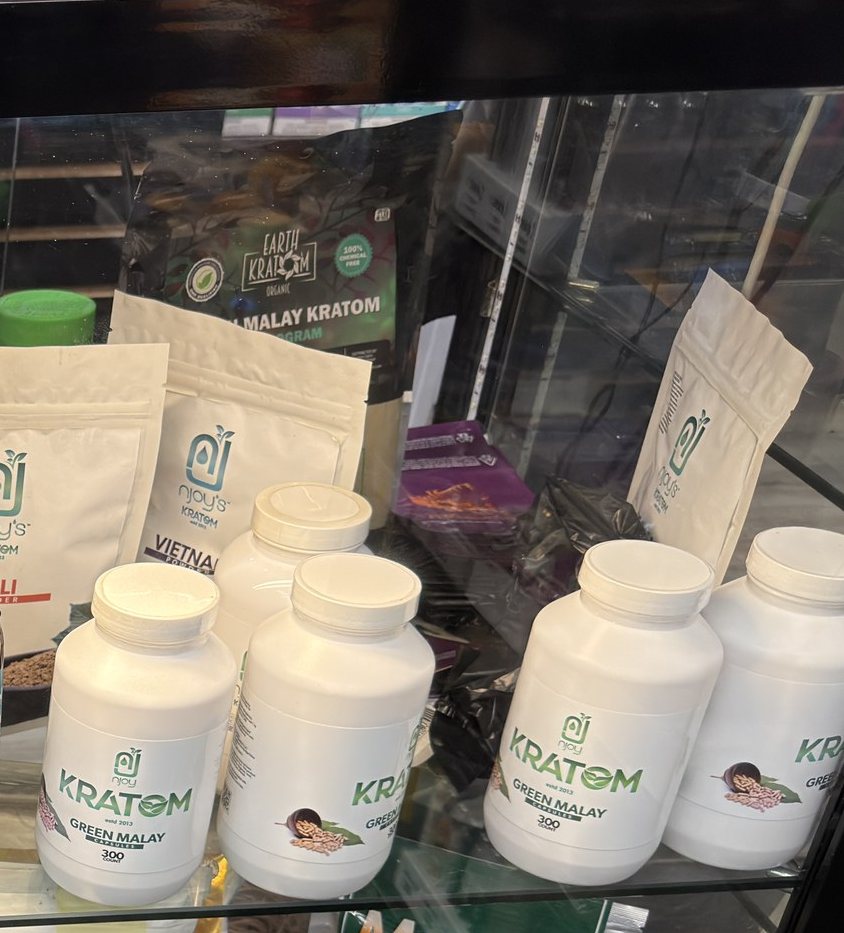 Earth Kratom and Njoy's kratom powders and capsules on a shelf behind the counter