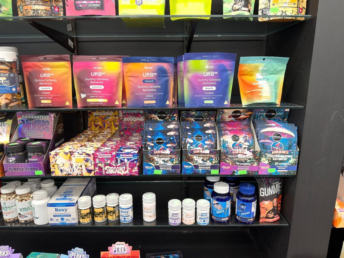 The lower shelf of the 21+ case, kratom capsules and powders behind the counter