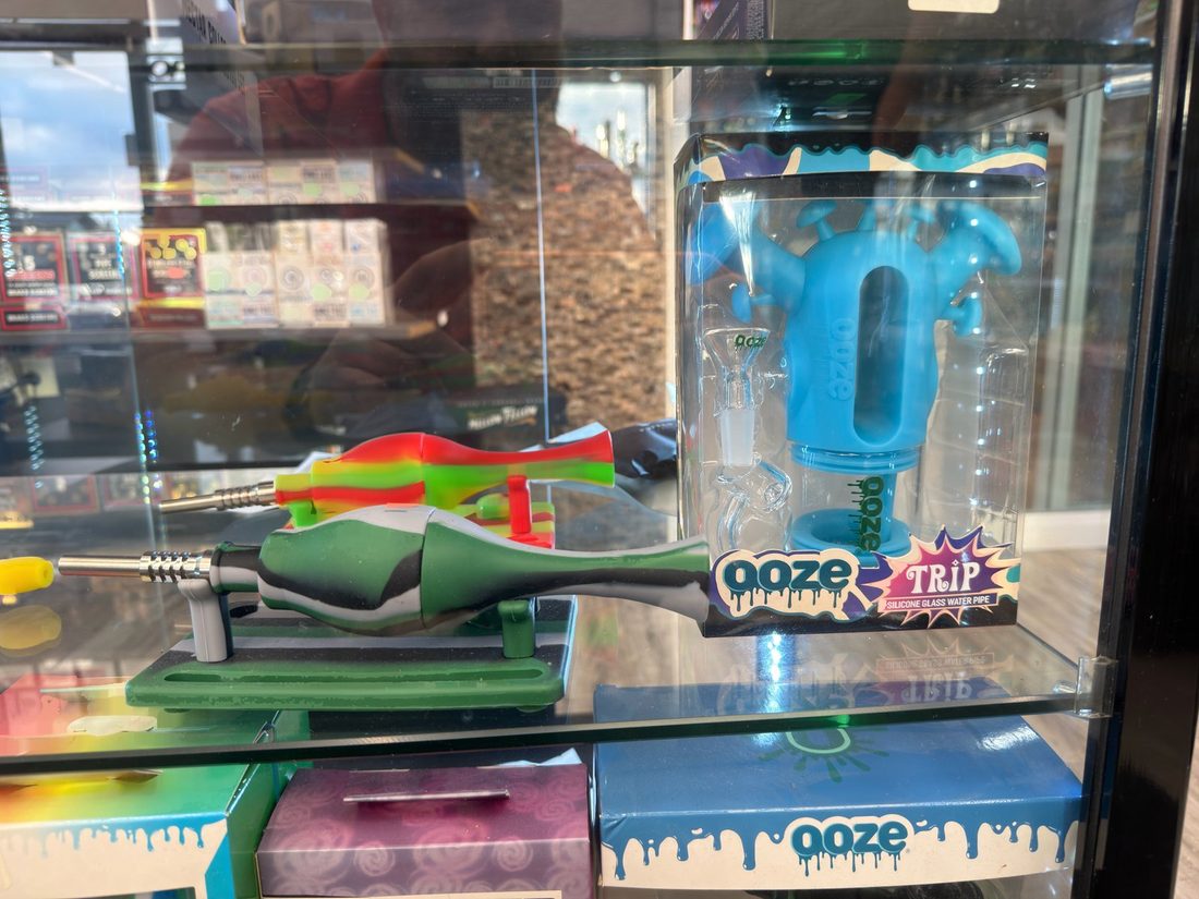 Boxed and unboxed Ooze silicone and glass water pipes on a display stand