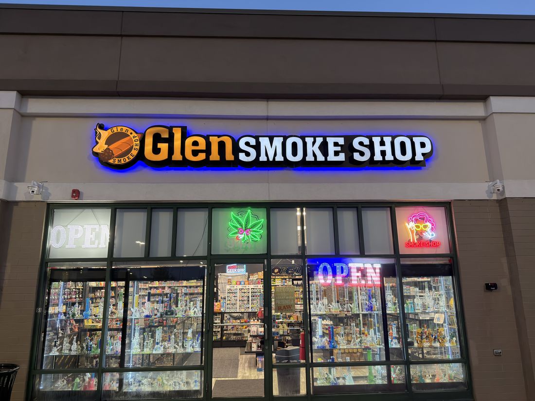 The Glen Smoke Shop sign lit up after dark