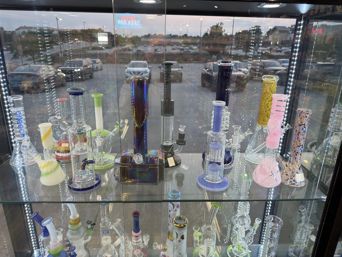 Beaker and straight-tube water pipes on a lit glass shelf